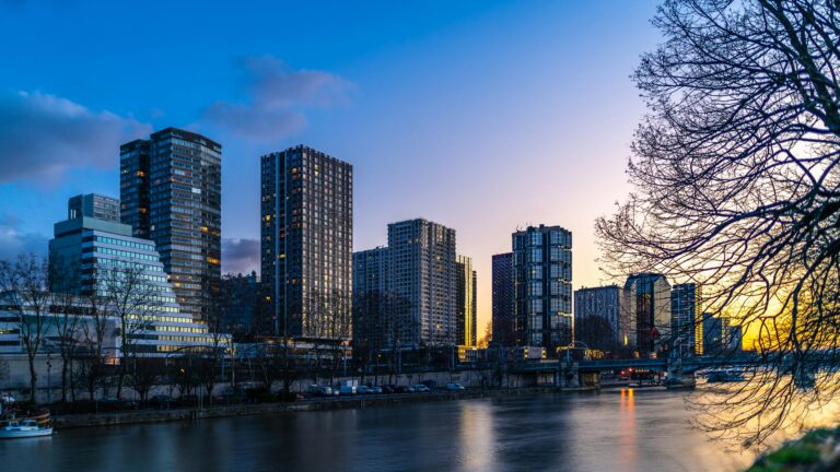 Stunning Paris skyline featuring modern skyscrapers by the river during sunset.